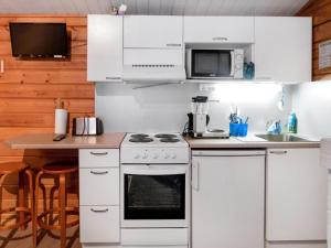 une cuisine avec une cuisinière blanche et un micro-ondes dans l'établissement Holiday Home Puolukka by Interhome, à Herttua