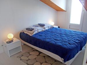 a bedroom with a bed with a blue comforter and a window at Holiday Home Les Jardins de l'Océan-38 by Interhome in Pontaillac