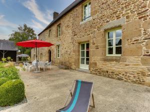 a patio with a chair and an umbrella and a table at Holiday Home La Tronçonnais by Interhome in Les Portes du Coglais