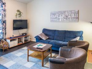 a living room with a blue couch and two chairs at Holiday Home Kisala by Interhome in Lahdenperä