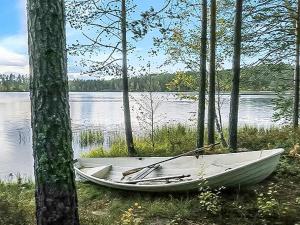 een witte boot die aan de rand van een meer ligt bij Holiday Home Kanerva by Interhome in Herttua