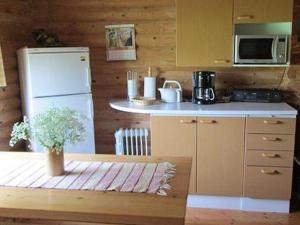 eine Küche mit einem weißen Kühlschrank und einer Mikrowelle in der Unterkunft Holiday Home Taukotupa by Interhome in Höytee