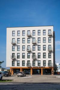 a large white hotel with a parking lot at Hotel Mamut in Poprad