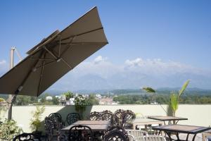 een groep tafels en stoelen met een paraplu bij Hotel Clarks Inn Suites Kangra in Kangra