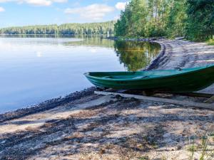 un bateau vert assis sur la rive d'un lac dans l'établissement Holiday Home Turulan hiekka by Interhome, à Hattusaari