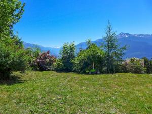 a green field with trees and mountains in the background at Chalet Chalet Aglaia by Interhome in Crans-Montana