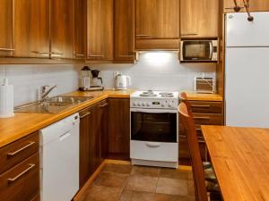 a kitchen with wooden cabinets and a white stove top oven at Holiday Home Lehtovilla a by Interhome in Äkäslompolo