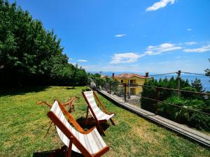 two wooden chairs sitting on the grass near a fence at Apartment Nives-1 by Interhome in Ičići