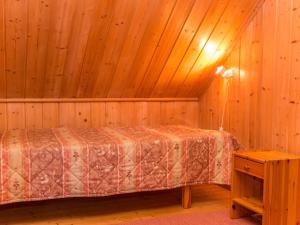 ein Schlafzimmer mit einem Bett in einem Zimmer mit Holzwänden in der Unterkunft Holiday Home Iltarusko by Interhome in Ruokonen