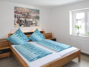 a bedroom with a bed with blue pillows and a painting at Apartment Nürburgblick by Interhome in Quiddelbach
