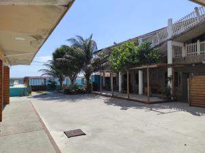 a building with palm trees in a parking lot at Pousada Laguna Beach Club in São Pedro da Aldeia