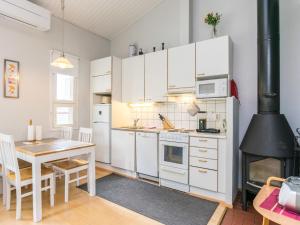 a kitchen with white cabinets and a table and a stove at Holiday Home Prokatti by Interhome in Lahdenperä