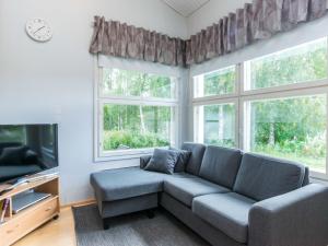 a living room with a couch and two windows at Holiday Home Prokatti by Interhome in Lahdenperä