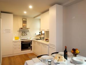 una cucina con armadi bianchi e un tavolo con cibo di Apartment Trilocale by Interhome a Olgiasca