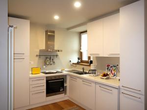 eine Küche mit weißen Schränken und einem Waschbecken in der Unterkunft Apartment Trilocale by Interhome in Olgiasca