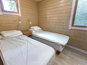 two beds in a room with wooden walls at Holiday Home Anttoora 6 by Interhome in Pori