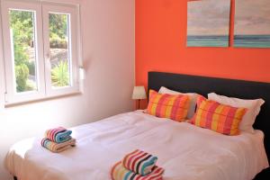 a bedroom with a bed with orange walls and a window at Casa Colorida in Porches +21 photos