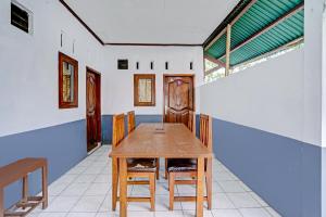 a dining room with a wooden table and chairs at SUPER OYO 90405 Penginapan Sasti Kuningan in Cirebon