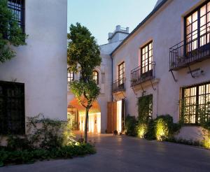 a white building with a tree in front of it at Hospes Palacio del Bailio, a Member of Design Hotels in Córdoba