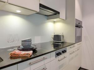 a kitchen with white cabinets and a counter top with wine glasses at Apartment Lantau by Interhome in Kandersteg