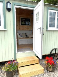 un cobertizo verde y blanco con una puerta y flores en Remarkable Shepherds Hut in a Beautiful Location, en Perth