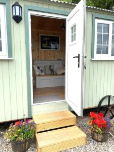 a green and white shed with a door and flowers at Remarkable Shepherds Hut in a Beautiful Location in Perth