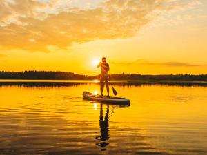 eine Person auf einem Paddleboard auf einem See bei Sonnenuntergang in der Unterkunft Holiday Home Hauki by Interhome in Hiukkajoki