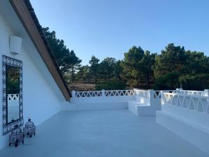 a white building with a balcony with trees in the background at Lovely 2-bedroom apartment- Comporta in Carvalhal