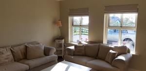 a living room with two couches and two windows at Relax at Safe Haven in Carlingford