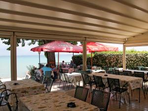 restauracja ze stołami, czerwonymi parasolami i oceanem w obiekcie Holiday Home Camping Wien-4 by Interhome w mieście Peschiera del Garda