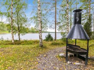 eine Glocke auf einer Bank neben einem See in der Unterkunft Holiday Home Muikku by Interhome in Hiukkajoki