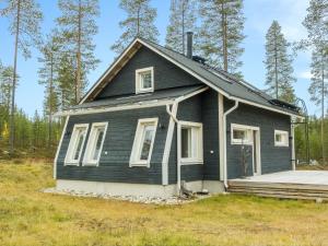 a small black house with a porch in a field at Holiday Home Aurora by Interhome in Narkaus