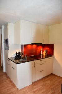 a kitchen with white cabinets and a red wall at Apartment Am Sonnenhang by Interhome in Churwalden