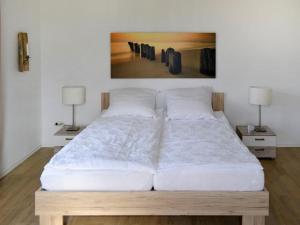 een slaapkamer met een groot wit bed met 2 lampen bij Apartment Am Rotenberg by Interhome in Detmold