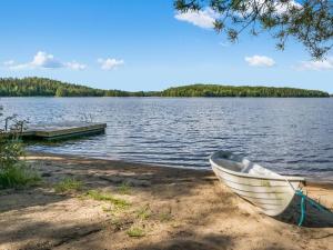 a boat on the shore of a lake with a dock at Holiday Home Mäntyranta by Interhome in Savonranta