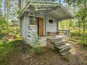 a small outhouse with a porch and stairs in the woods at Holiday Home Mäntyranta by Interhome in Savonranta