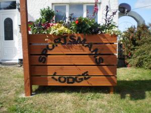 a wooden sign with graffiti on it in front of a house at Sportsmans Lodge Bed and Breakfast in Amlwch