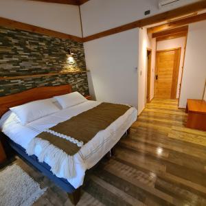 uma cama num quarto com uma parede de tijolos em Cerveceria y Hosteria Lican em Villarrica
