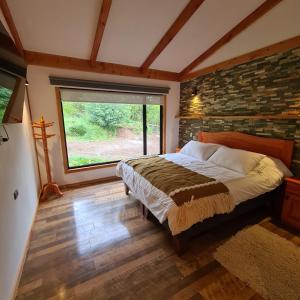 1 dormitorio con cama y pared de ladrillo en Cerveceria y Hosteria Lican, en Villarrica
