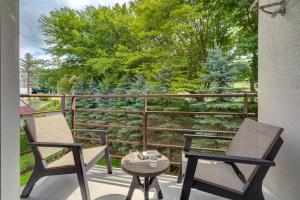 2 Stühle und ein Tisch auf einem Balkon mit Bäumen in der Unterkunft Apartament Ola in Krynica-Zdrój