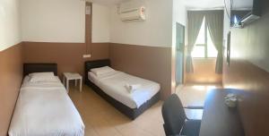 sypialnia z 2 łóżkami i krzesłem w obiekcie Lih Pin Hotel w mieście Sungai Petani