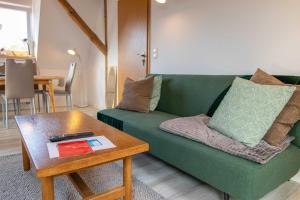 uma sala de estar com um sofá verde e uma mesa em Ferienwohnung Kogeler See em Kogel