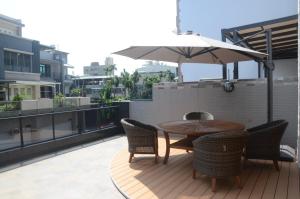 un patio con mesa, sillas y sombrilla en Rebecca Hostel, en Chaozhou