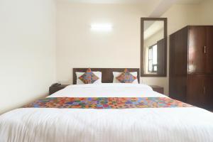 a bedroom with a large white bed with a mirror at FabHotel Kutighar Regency in Gangtok