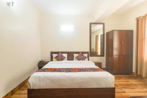 a bedroom with a large bed and a mirror at FabHotel Kutighar Regency in Gangtok
