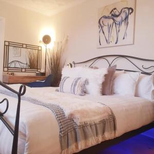Schlafzimmer mit einem Bett mit weißer Bettwäsche und Kissen in der Unterkunft The Blue Horse Suite at The Grumpy Schnauzer B&B Private Hot Tub, Gym, Breakfast, Stunning! in Airdrie