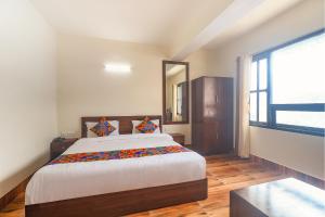 a bedroom with a large bed and a large window at FabHotel Kutighar Regency in Gangtok