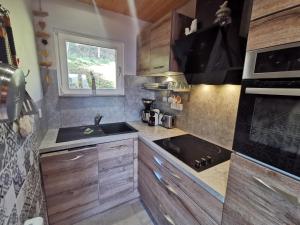 a kitchen with wooden cabinets and a sink and a stove at les Genêts in La Bresse