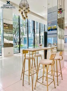 une table et des chaises dans une pièce avec fenêtres dans l'établissement Bangkok Midtown Hotel, à Bangkok