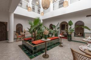 eine Lobby mit einem Sofa, Tischen und Pflanzen in der Unterkunft Riad Babouchta & Spa in Marrakesch